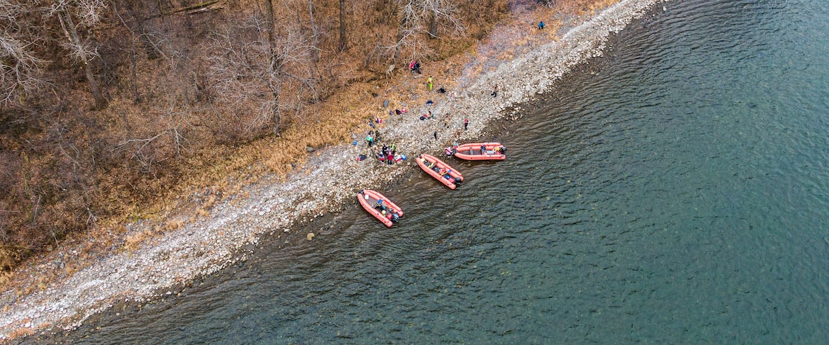 An aerial view of a riverbank with people and inflatable boats.