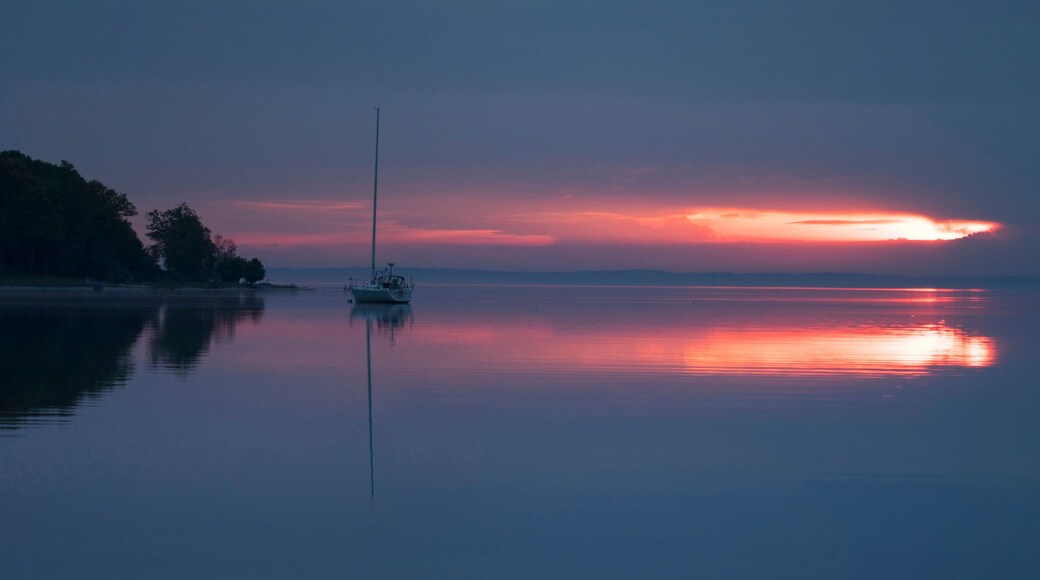Sunrise over bay in northern Michigan with sailboat and foggy shore