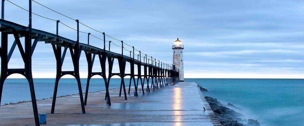 Une jetée qui s’avance dans la mer, avec un phare à son extrémité.