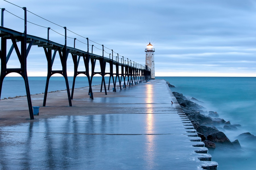 Un muelle que se adentra en el mar con un faro al final.