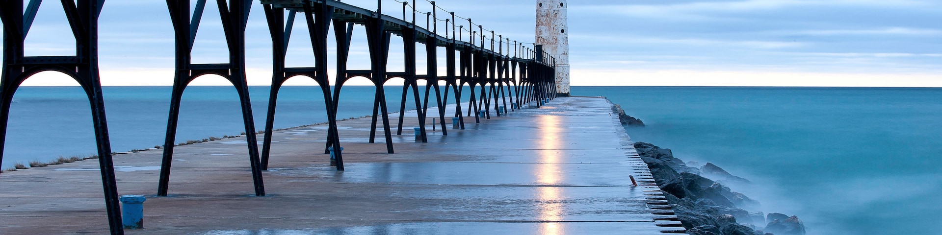 Un muelle que se adentra en el mar con un faro al final.