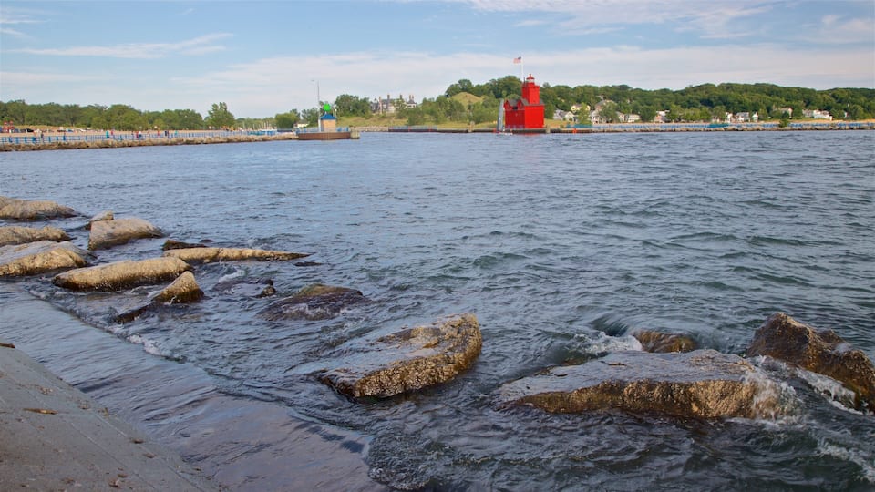 A rocky shoreline with a red lighthouse in the distance.