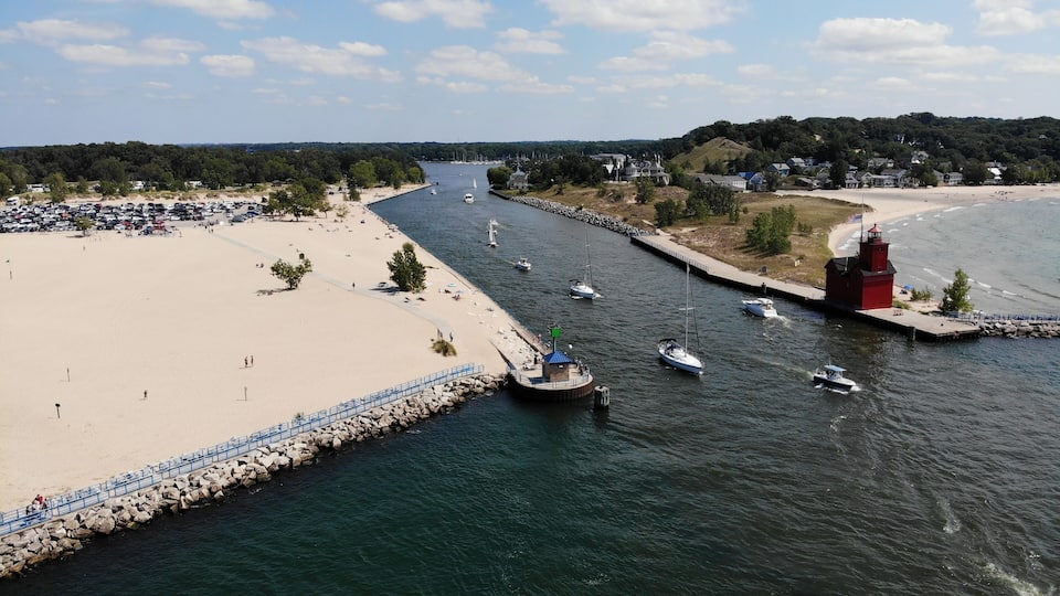 A coastal town with a sandy beach, a lighthouse, and several boats on the water.