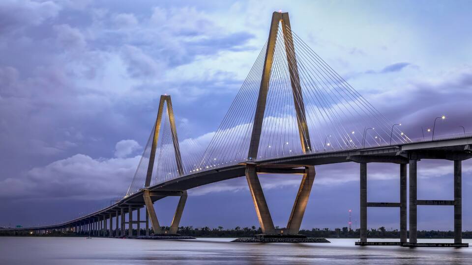 A long suspension bridge with tall towers and cables, spanning over a body of water.