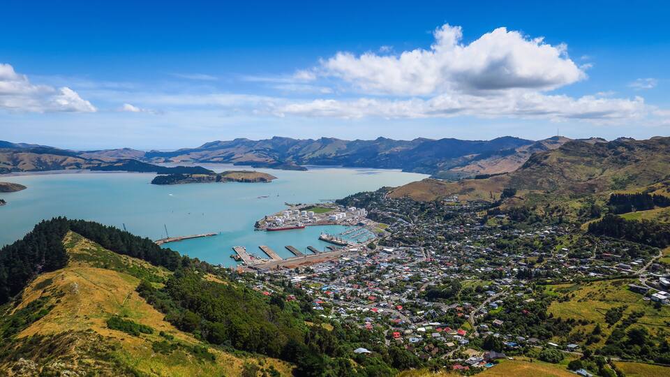 A coastal town with a harbor, mountains in the background, and a clear blue sky.