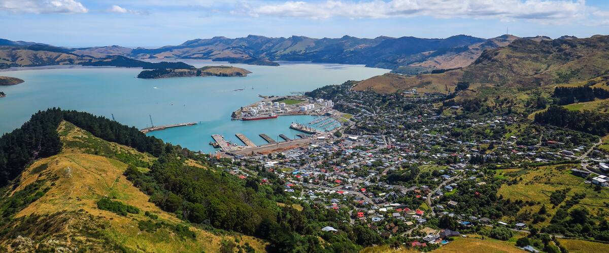 A coastal town with a harbor, mountains in the background, and a clear blue sky.