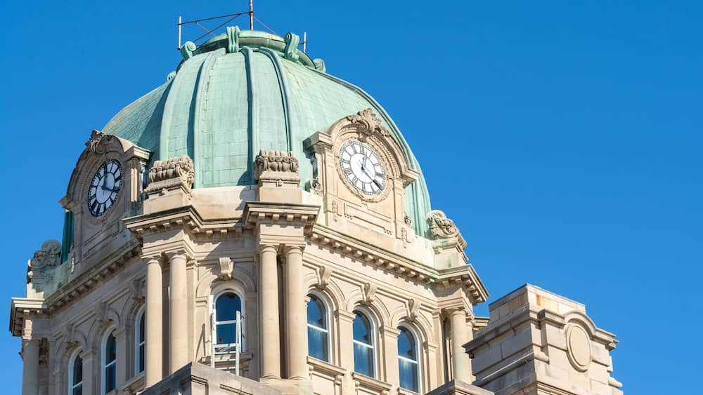 A building with a green dome and two clocks on its facade.