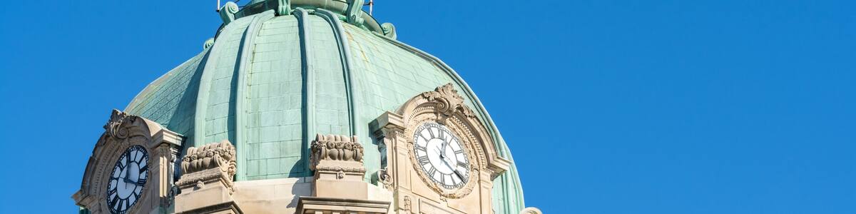 A building with a green dome and two clocks on its facade.