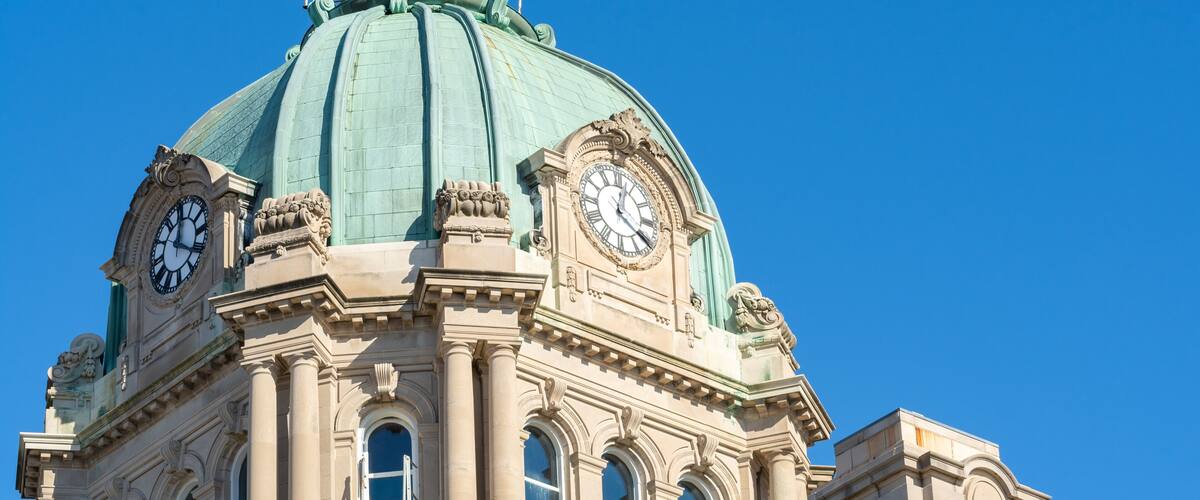 Ein Gebäude mit einer grünen Kuppel und zwei Uhren an der Fassade.