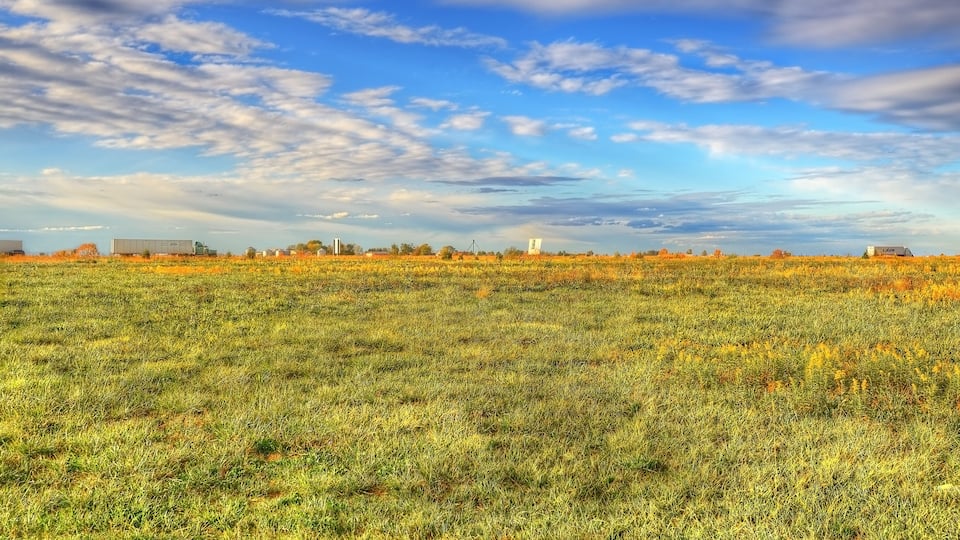 A vast field with a clear sky and scattered clouds.