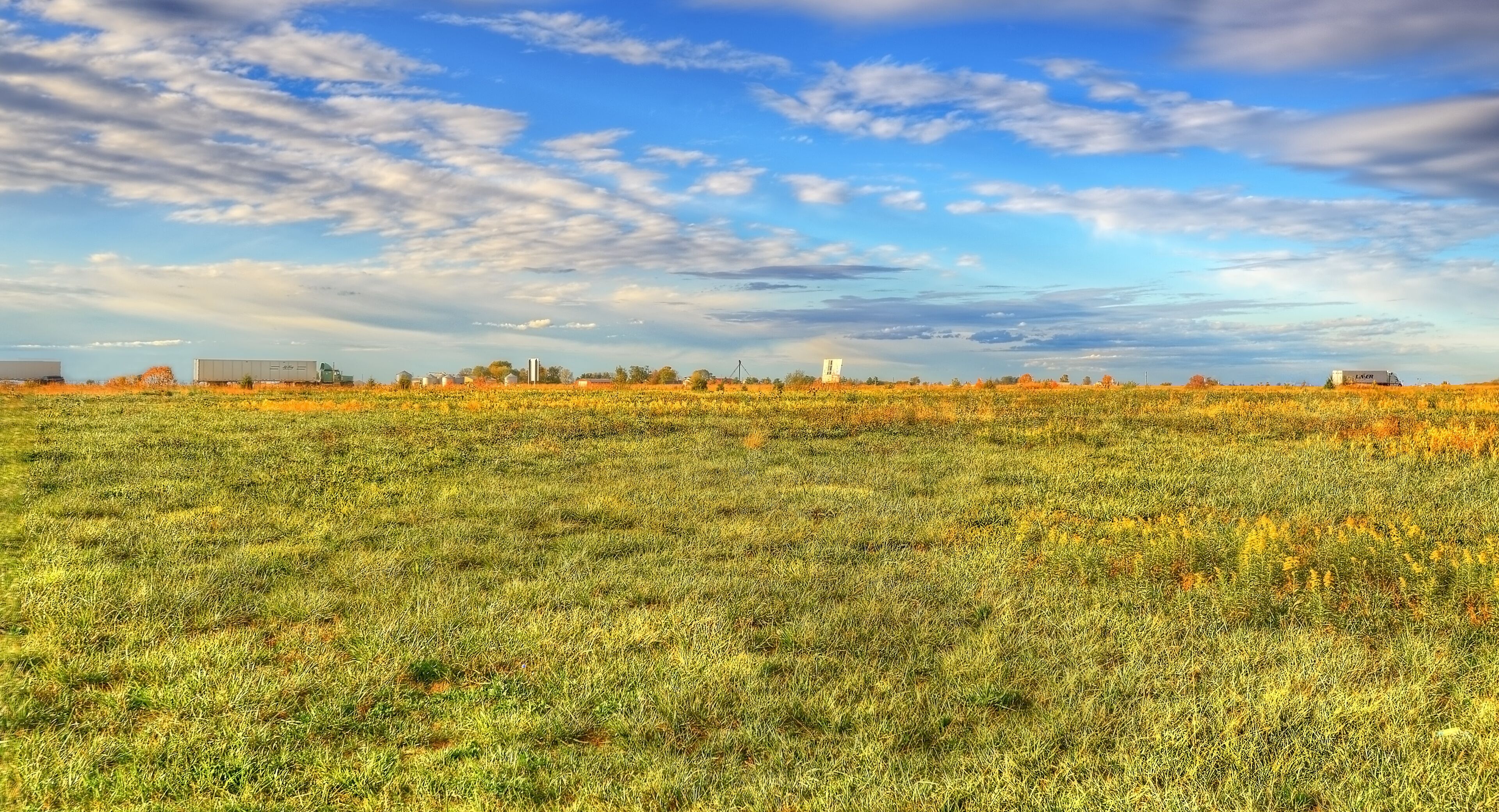 A vast field with a clear sky and scattered clouds.