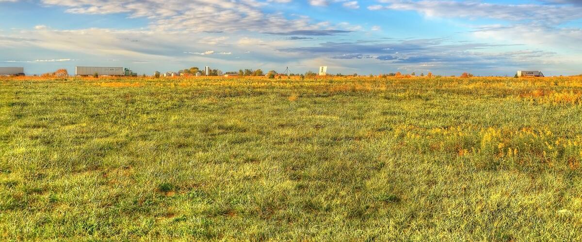 A vast field with a clear sky and scattered clouds.