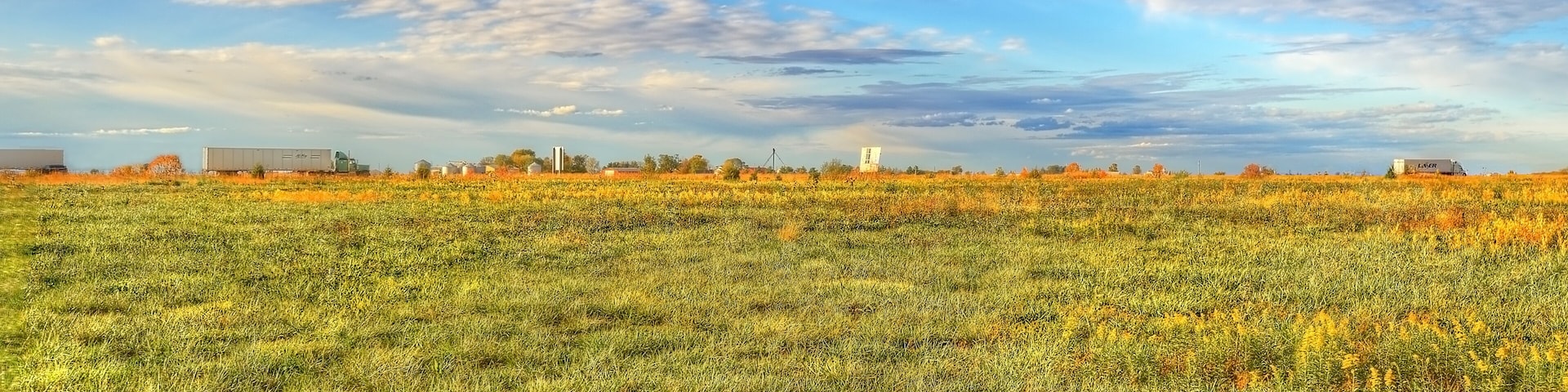 A vast field with a clear sky and scattered clouds.