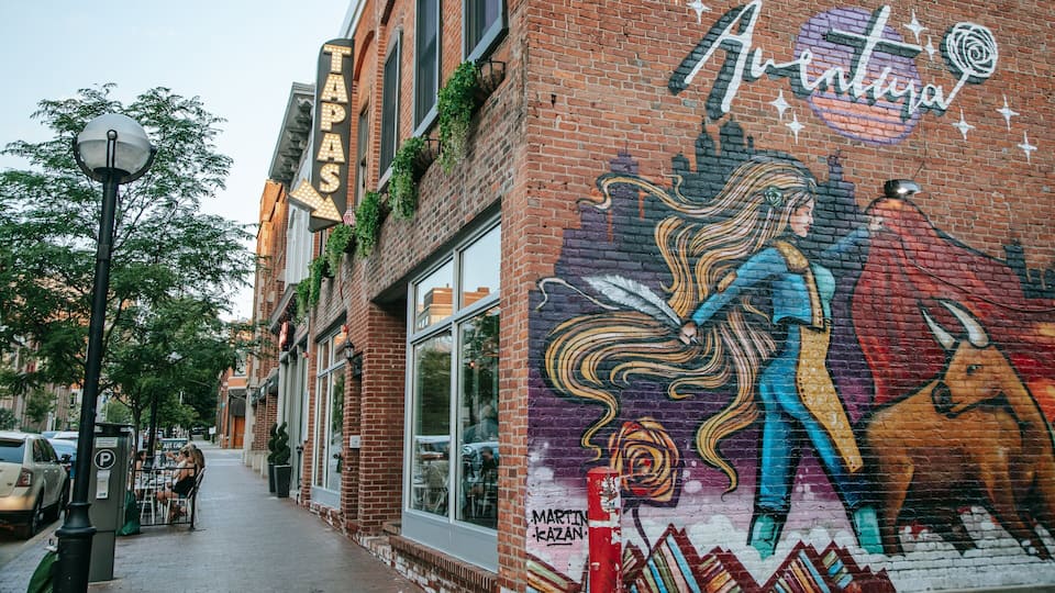 A mural on a brick building with a sign that reads "TAPAS" and "Aventura".