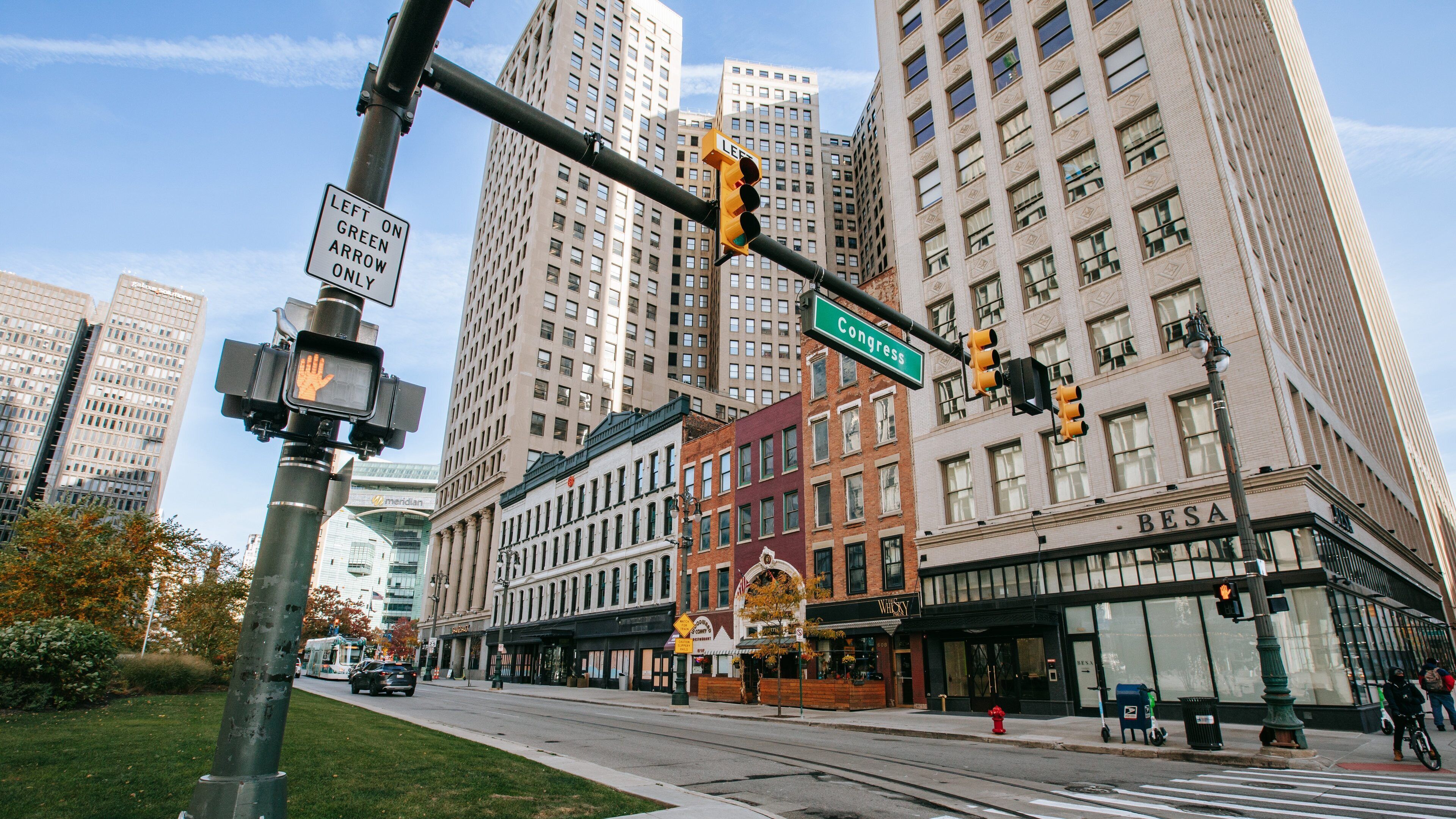 A city intersection with traffic lights, a street sign for Congress, and tall buildings in the background.