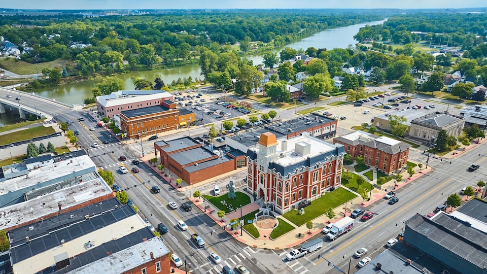 An aerial view of a town with a river, buildings, and a clock tower.