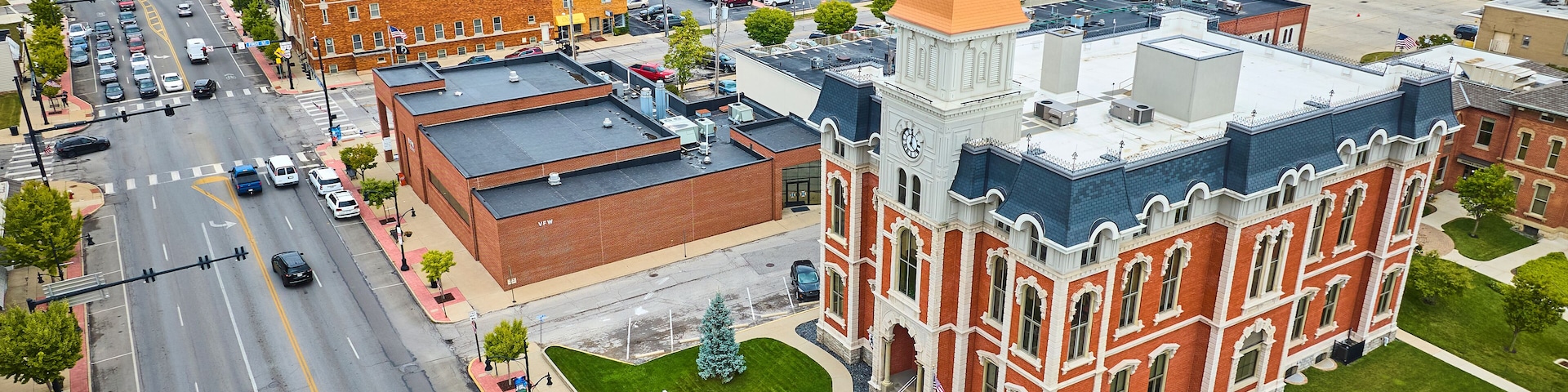 A town square with a historic building, a parking lot, and a river in the background.
