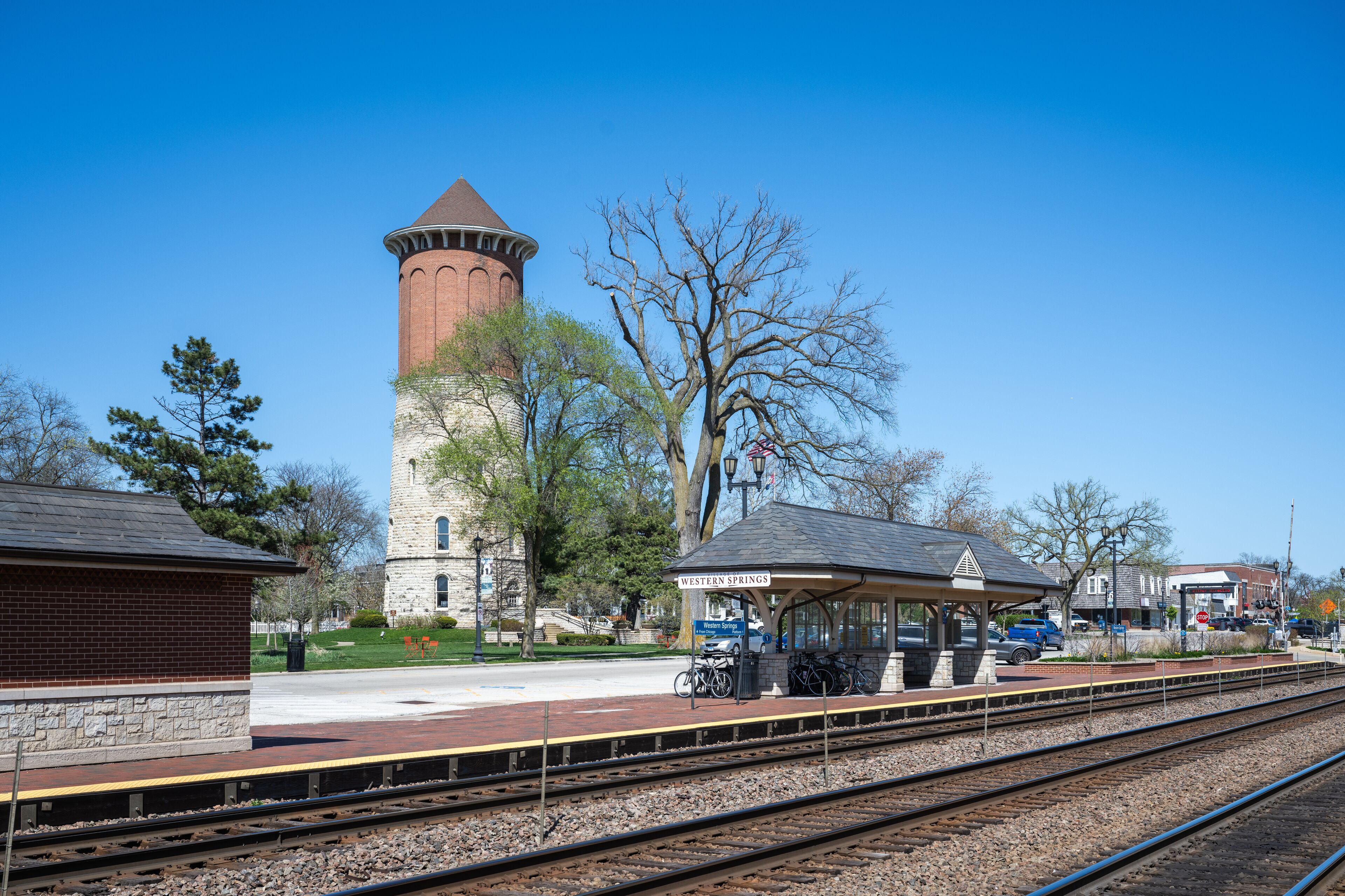 A train station with a brick building, a covered waiting area, and a tower.