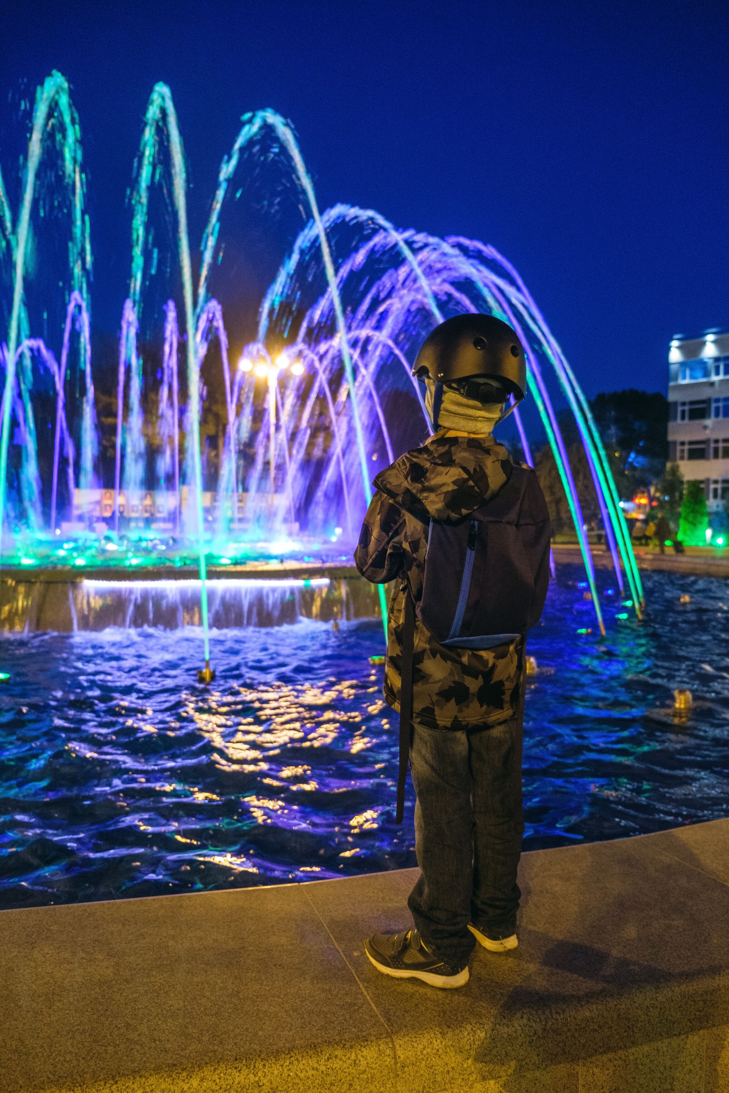 Small kid play with colorful fountain at Lima park