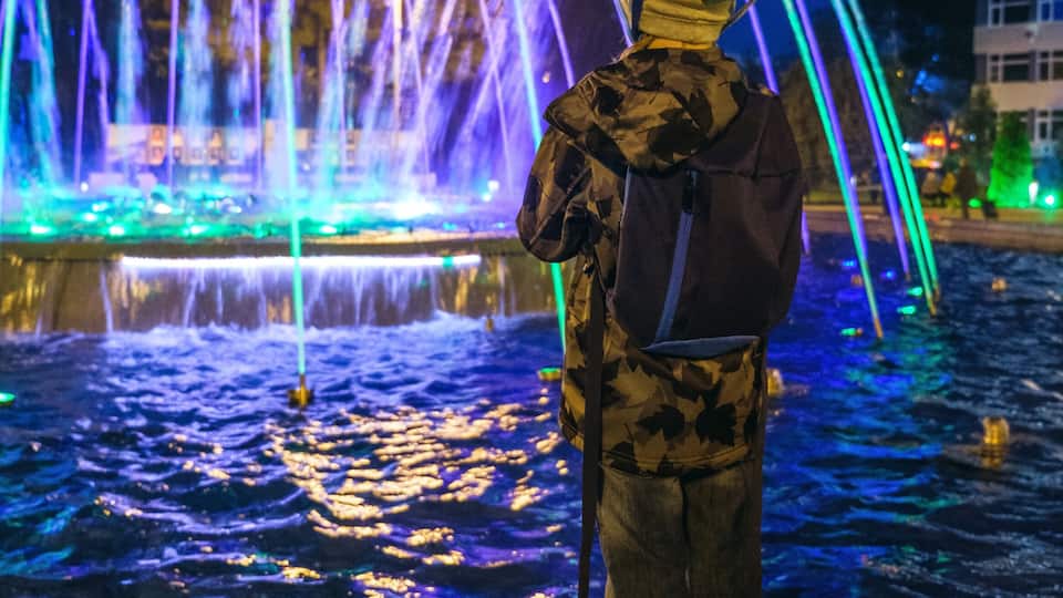 Small kid play with colorful fountain at Lima park