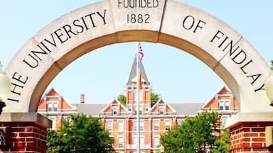 Um arco com a inscrição "The University of Findlay Fundada 1882" dando acesso a um edifício.