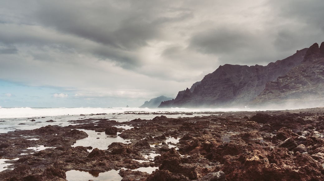 Punta del Hidalgo, Tenerife, Espania - October 27, 2018: Panorama of the rocky beach of Punta de Hidalgo and the waves breaking at the rocks, taken on a rainy day