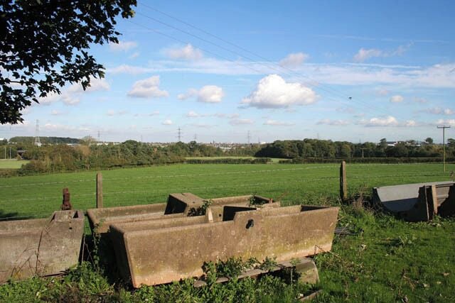 Farmland at Warren Farm Junction 21 0n the M1 is behind the trees in the centre and the M69 goes off to the left. The woodland to the right is Freeboard Spinney. The preponderance of electricity pylons is because the huge Enderby electricity substation is in the adjacent square to the west. The cattle drinking troughs in the foreground are made of concrete.