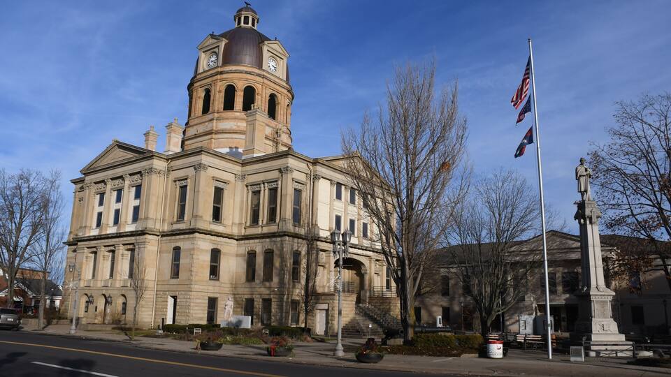 A historic building with a prominent clock tower and a statue.