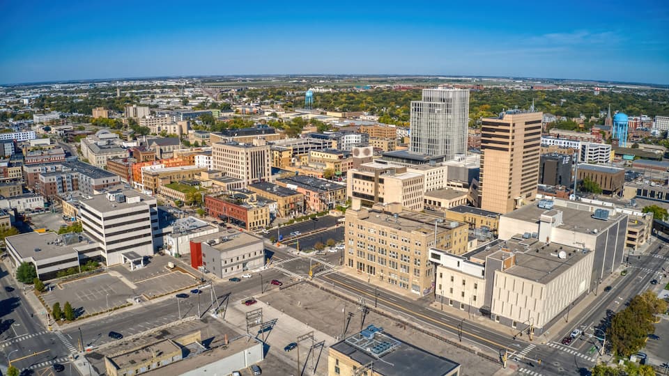 A cityscape with a mix of modern and older buildings, a prominent water tower, and a clear blue sky.
