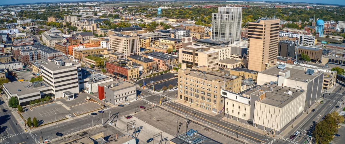 A cityscape with a mix of modern and older buildings, a prominent water tower, and a clear blue sky.