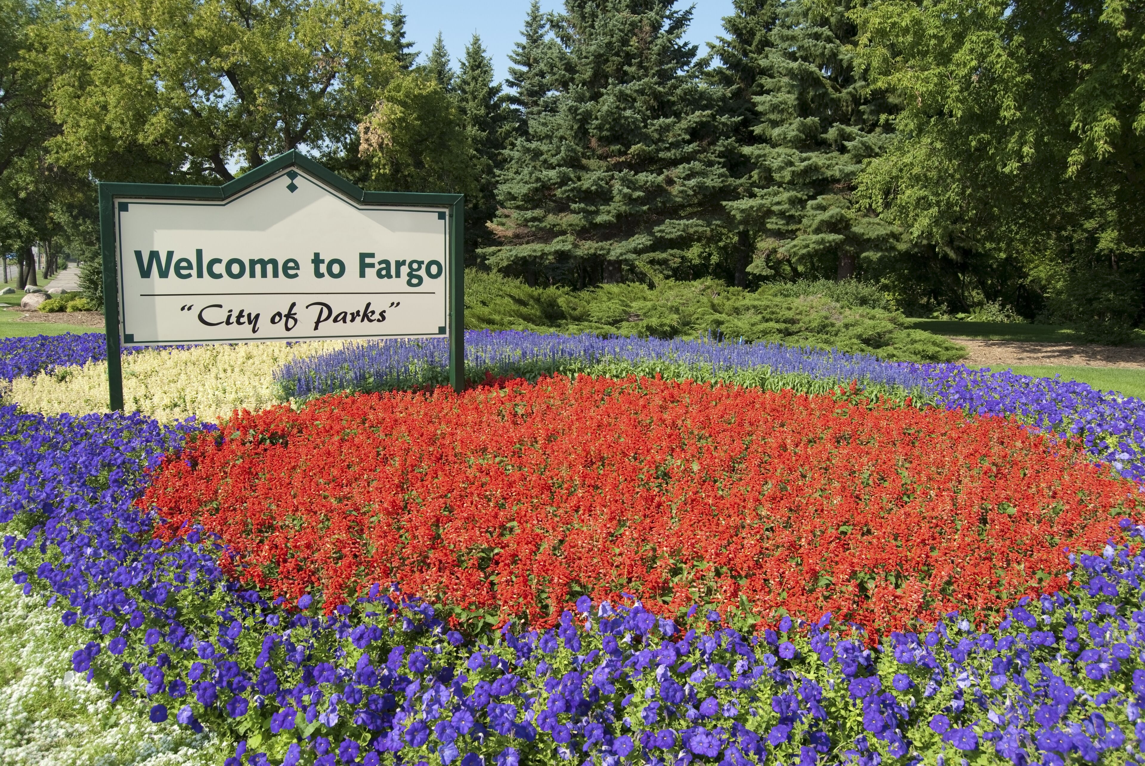 A welcome sign to Fargo, surrounded by colorful flower beds.