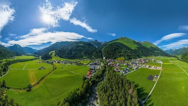 A mountainous landscape with a river, green fields, and a small village.