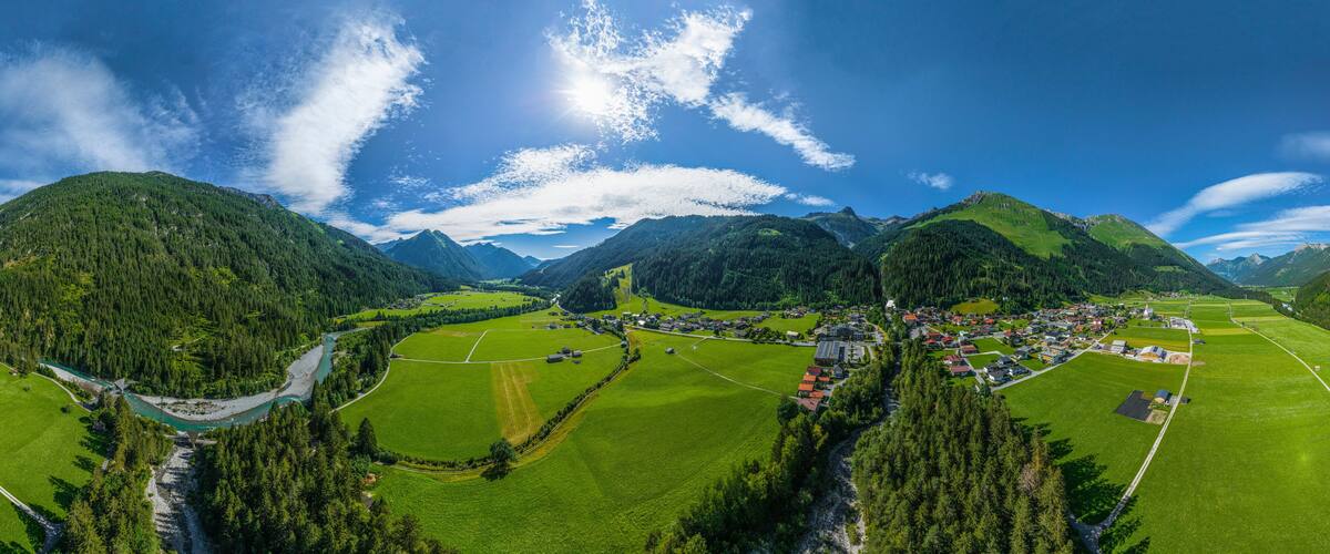 A mountainous landscape with a river, green fields, and a small village.