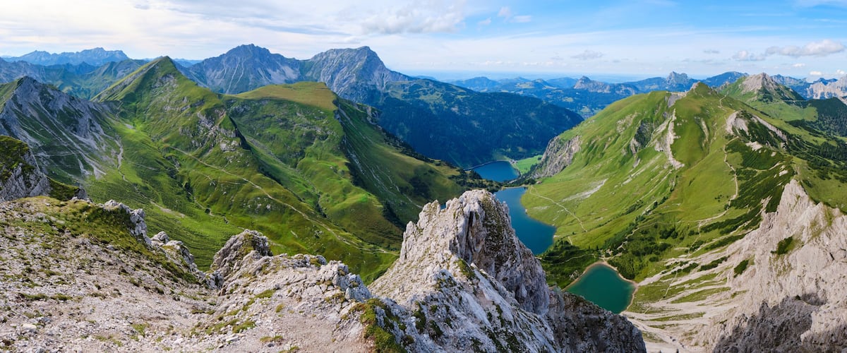 A mountainous landscape with a valley, a lake, and distant peaks.