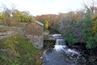 Un moulin en bois situé près d’une cascade, dans une zone boisée.