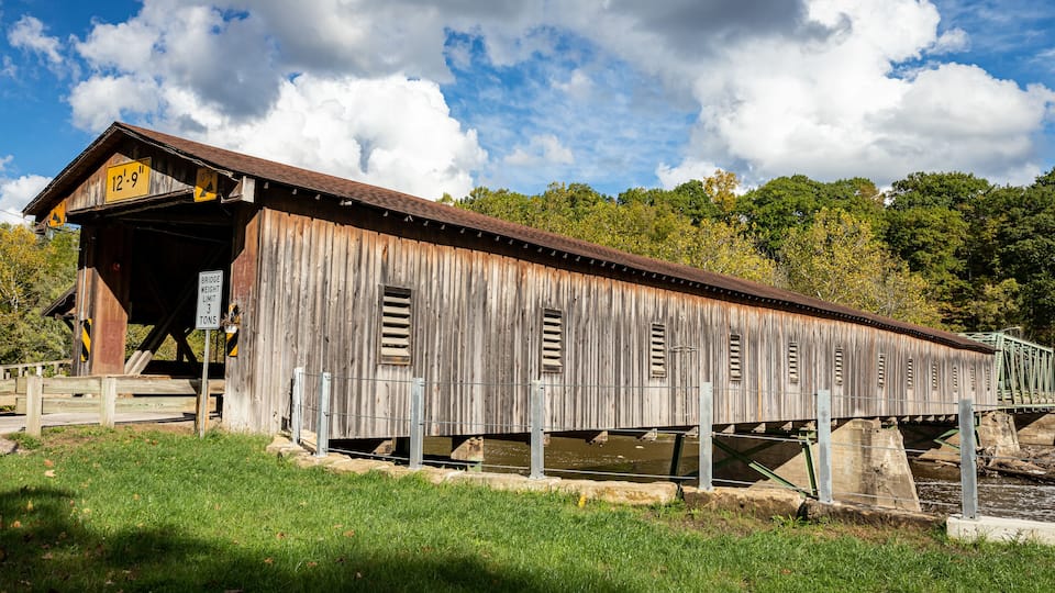 A covered wooden bridge with a sign indicating a weight limit of 3 tons.