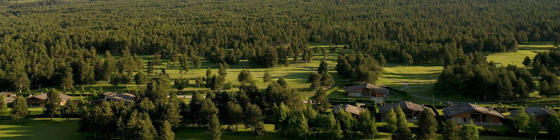A mountainous landscape with dense forests and a golf course.