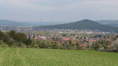 A town nestled in a valley with a prominent hill in the background.