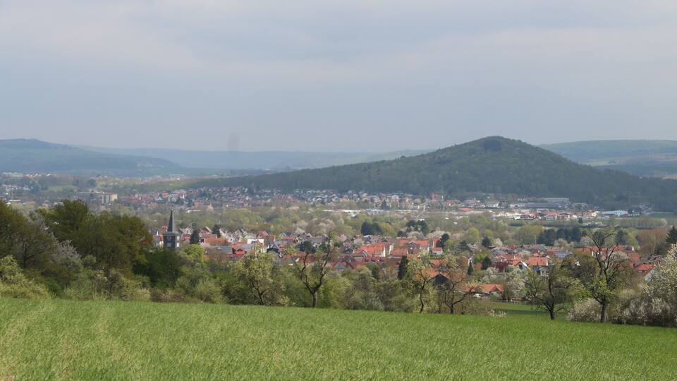 A town nestled in a valley with a prominent hill in the background.