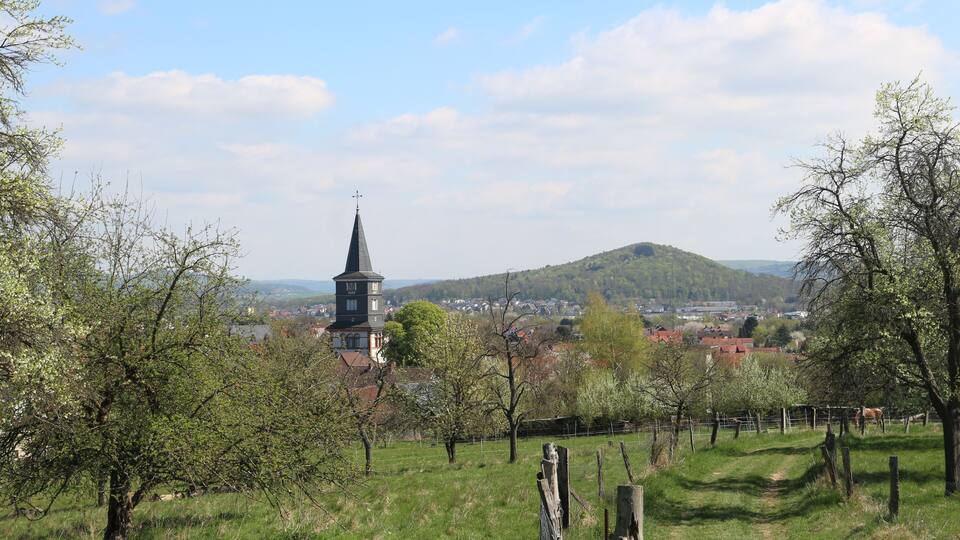 A church tower, a hill, and a town in the background.