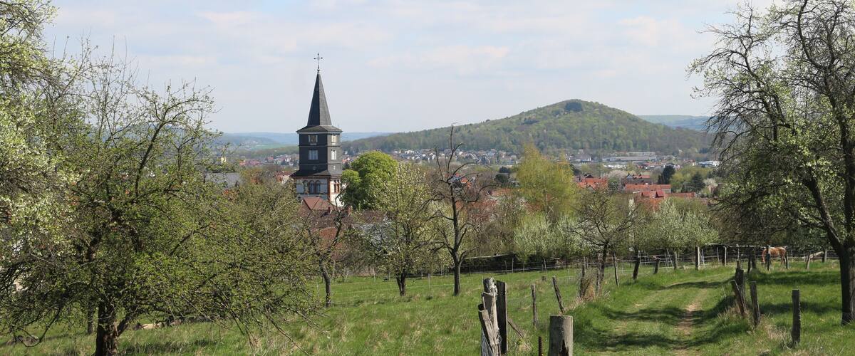 A church tower, a hill, and a town in the background.
