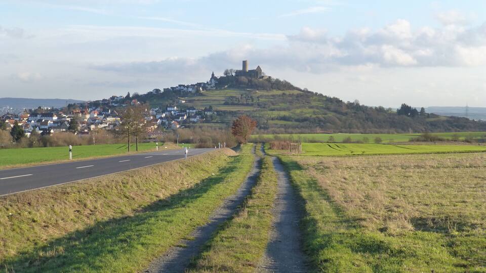 A rural landscape with a road leading to a hilltop with a castle.