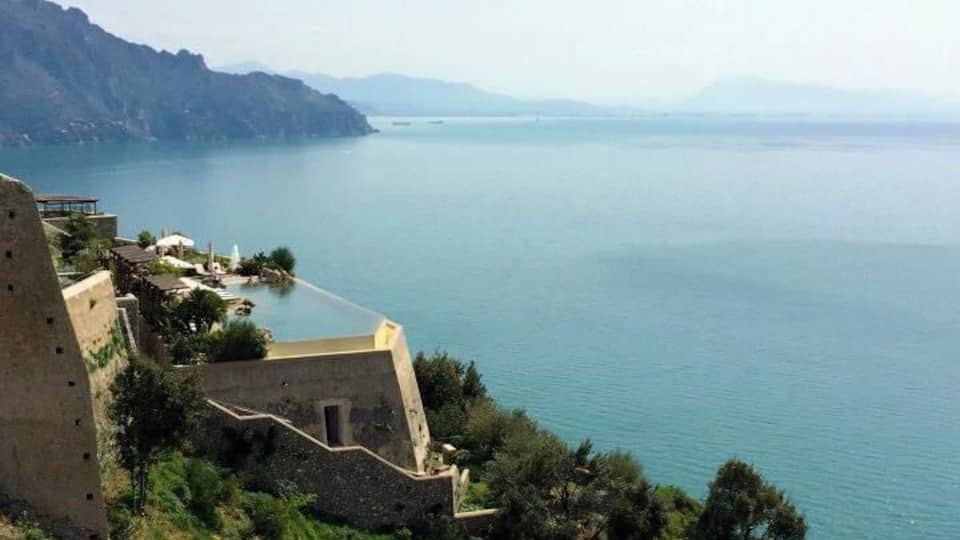 A coastal cliff with a building and a sea view.