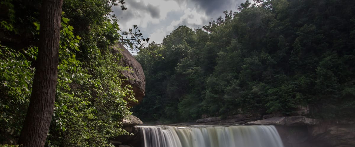 A waterfall cascading over rocks with people observing it.