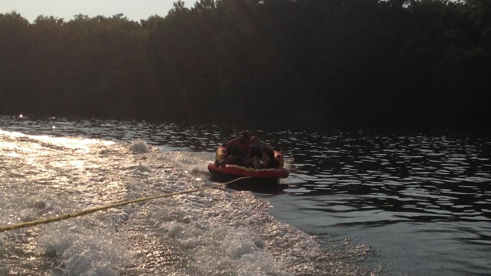 A person wakeboarding on a lake with trees in the background.