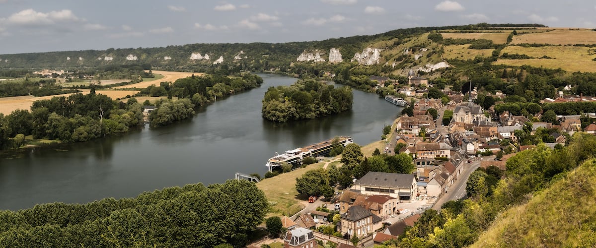 A river winding through a town with historic buildings and greenery.