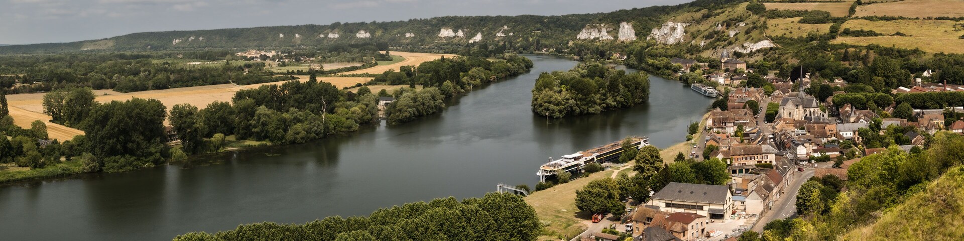 A river winding through a town with historic buildings and greenery.