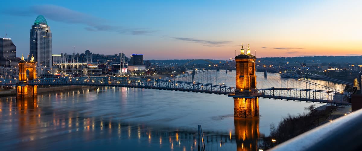 A bridge spanning a river with city buildings in the background.