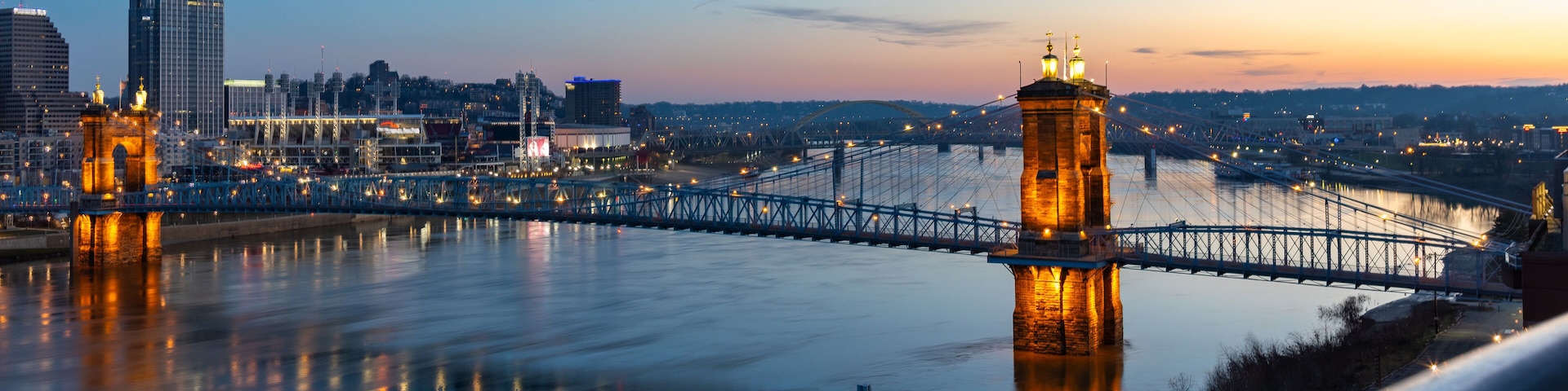 A bridge spanning a river with city buildings in the background.