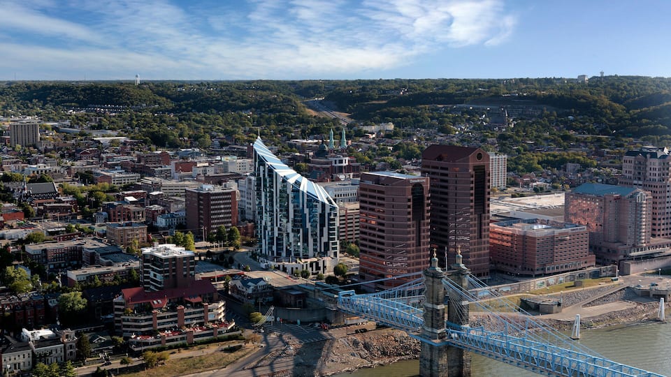 A cityscape with a prominent blue bridge over a river, surrounded by various buildings and greenery.